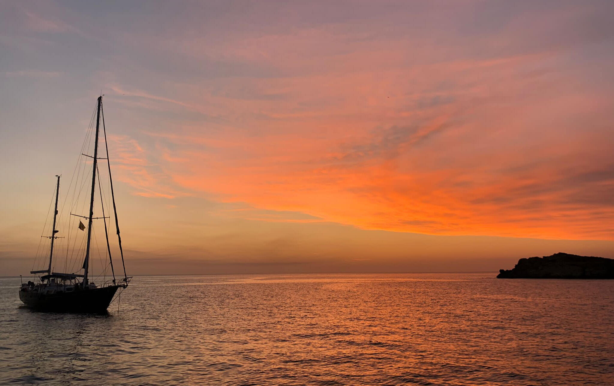 El velero Paradise fondeado en una cala de aguas turquesas en Formentera, ideal para un charter consciente.